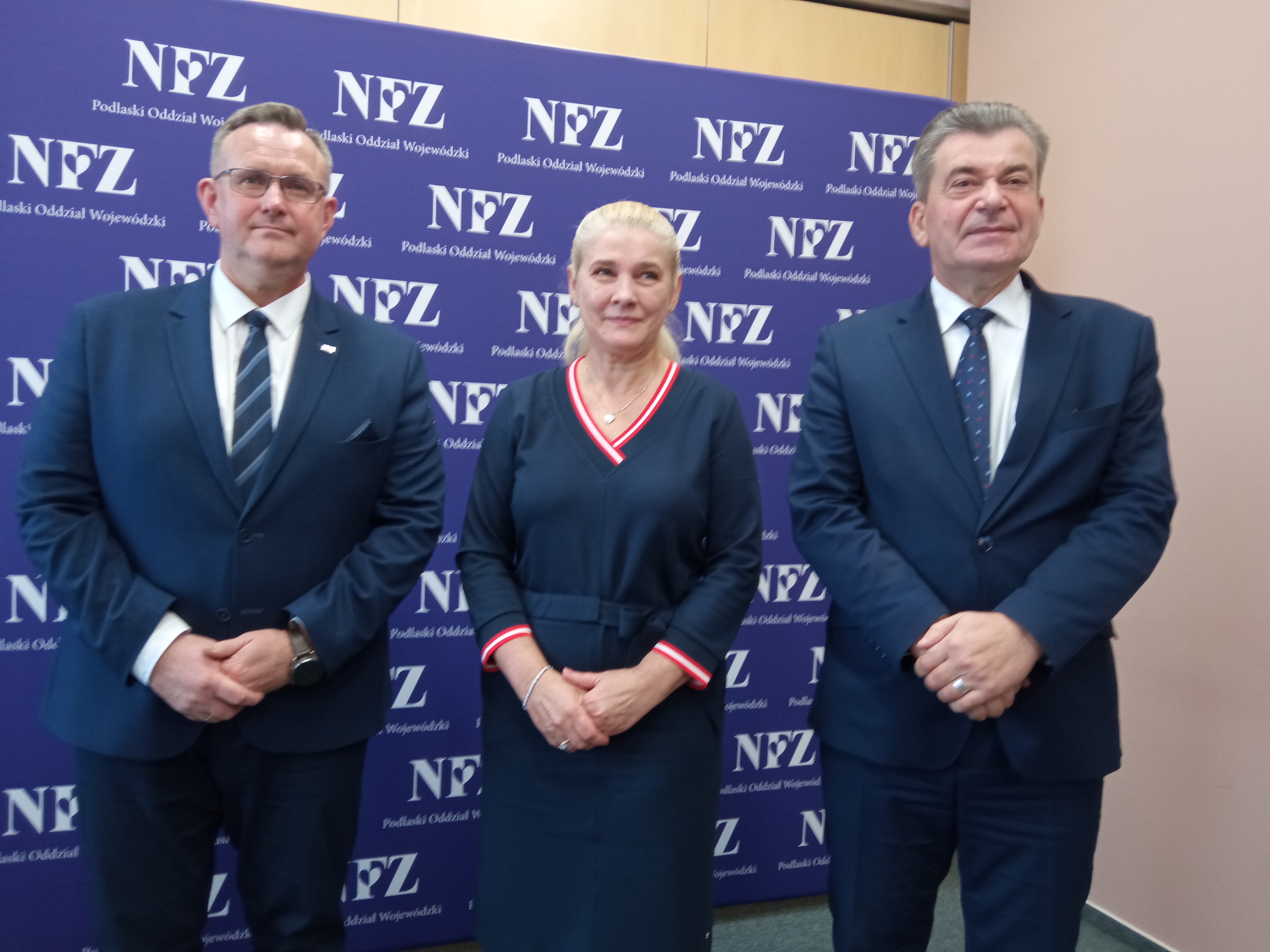 Kobieta i dwaj mężczyźni stoją obok siebie na konferencji prasowej