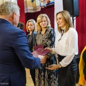 Mężczyzna wręcza dyplom kobiecie. Obok stoją inne panie