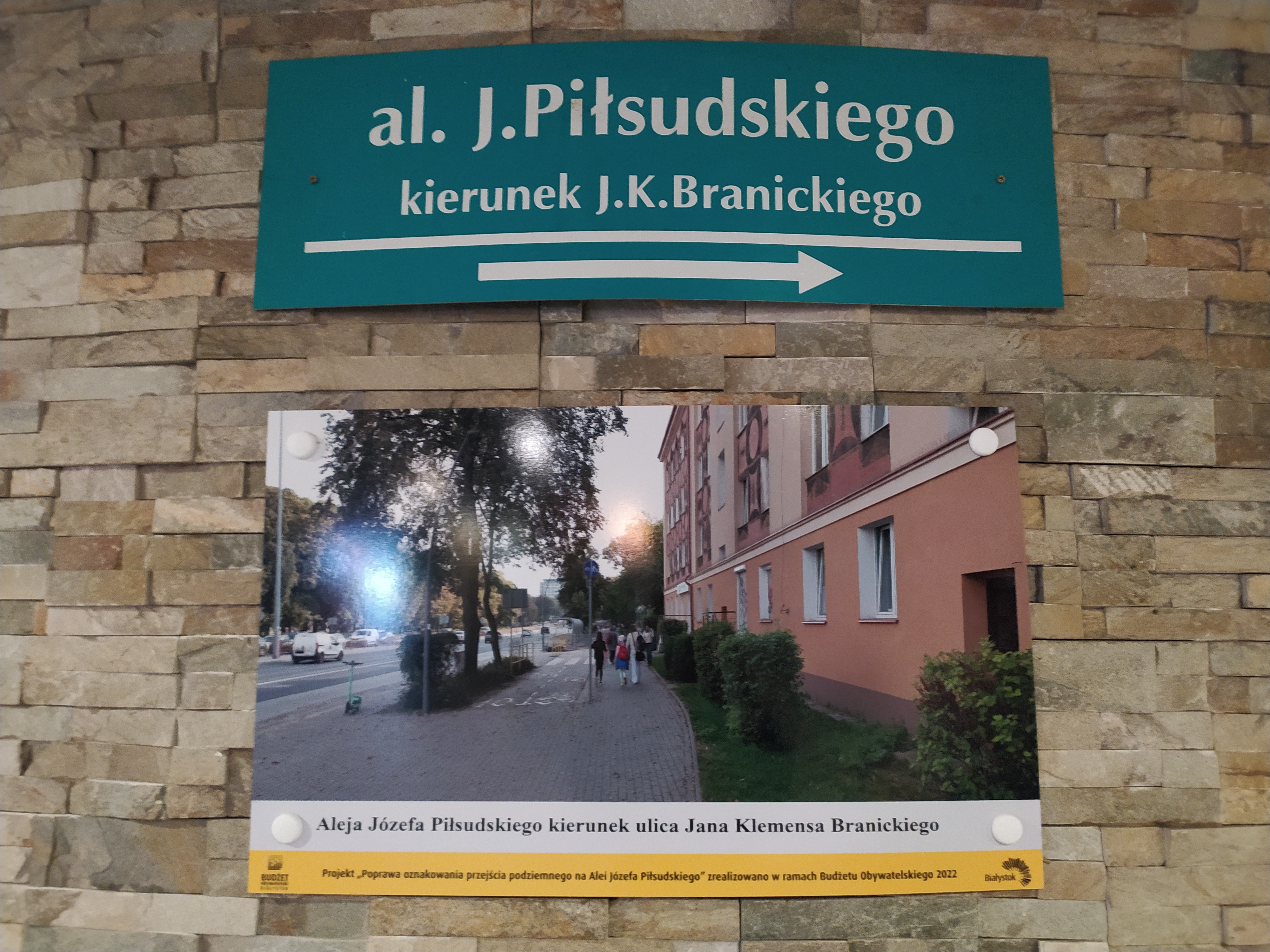 Tabliczka z napisem ulicy, i kierunkiem wyjścia, poniżej zdjęcie ulicy i budynku