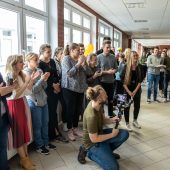 Grupa studentów stoi w hlou i słucha wystąpień