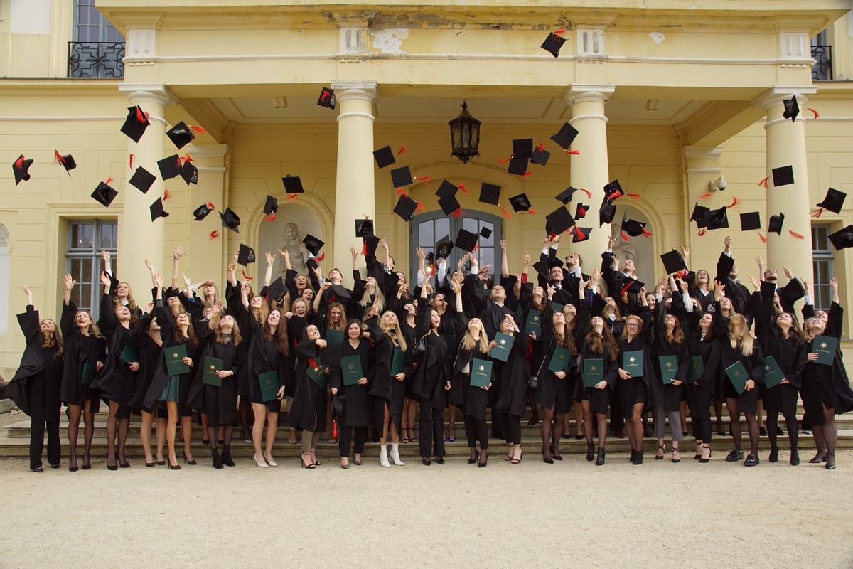 Kilkudziesięciu studentów w togach podrzuca birety