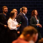 Sześć elegancko ubranych osób w ciemnej sali