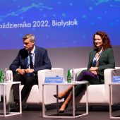 Kobieta i mężczyzna siedzą w fotelach na scenieotelu trzyma mikrofon przy ustach, obok niej siedzi mężczyzna