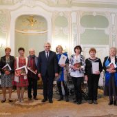 Grupa osób stoi z duplomami obok prezydenta miasta