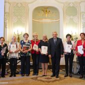 Grupa osób stoi z duplomami obok prezydenta miasta