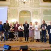Grupa osób stoi z duplomami obok prezydenta miasta