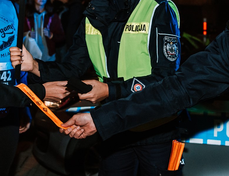 Policjnci zakładają odblaskowe opaski na rękaw innej osoby