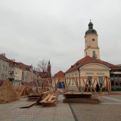 Drewniane elementy szopki przygotowane do montażu, w tle Ratusz