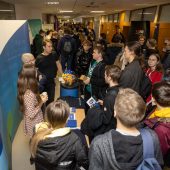 Tłum młodych ludzi stoi przy stoiskach wystawienniczych firm