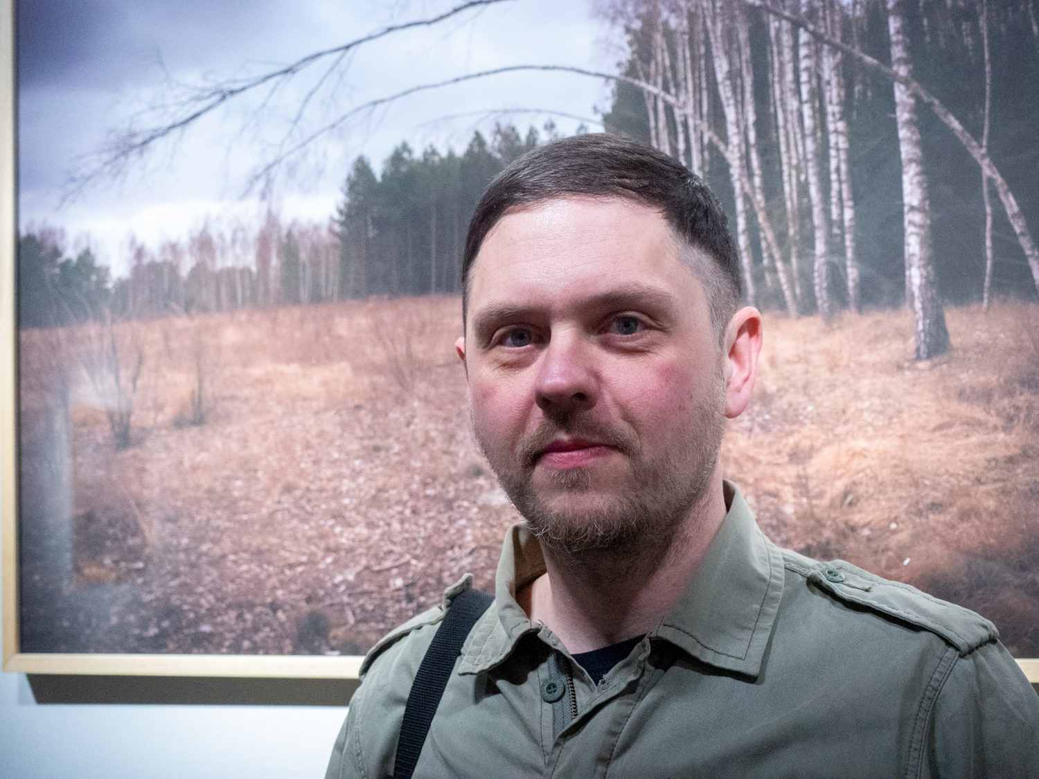 Mężczyzna w średnim wieku na tle fotografii łąki i lasu