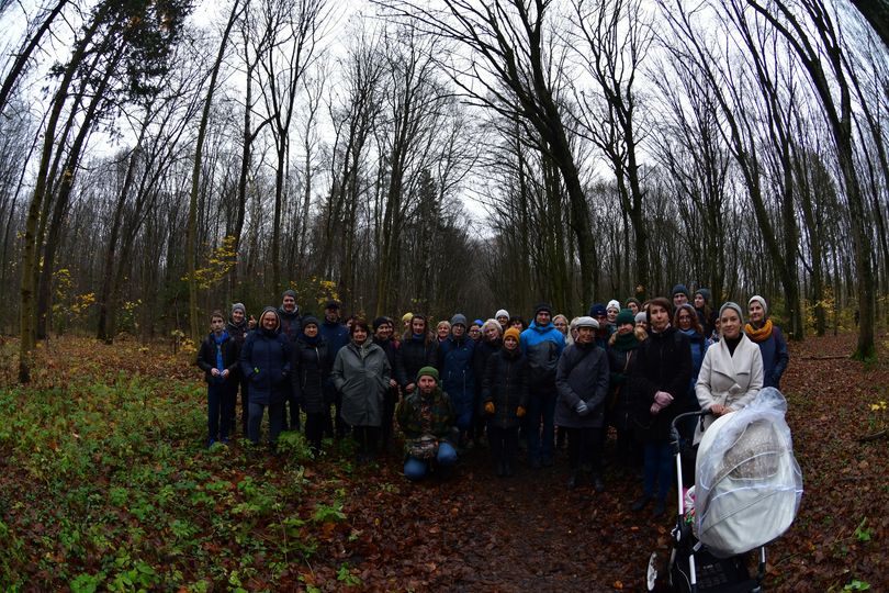 Grupa około 30 osób stoi w lesie jesienią