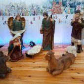 Na podeście figurki: Maryi, żłóbek, pastuszkowie i zwierzeta, w tle grafika miasta