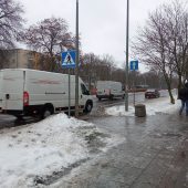 Samochody jazdą ulicą w Białymstoku, obok oblodonym chodnikiem idzie mężczyzna