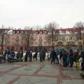 Długa kolejkaosób ze sztucznymi choinkami czeka na wymianę na drzewka w doniczce