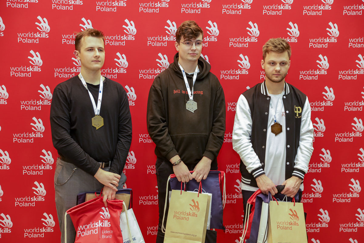 trezch młodych mężczyzn stoi z nagrodami i medalami