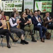 Grupa osób siedzi na krzesłąch