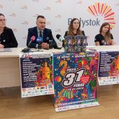 Cztery osoby siedzą za stołem, przed nimi stoją puszki WOŚP 2023 i plakaty