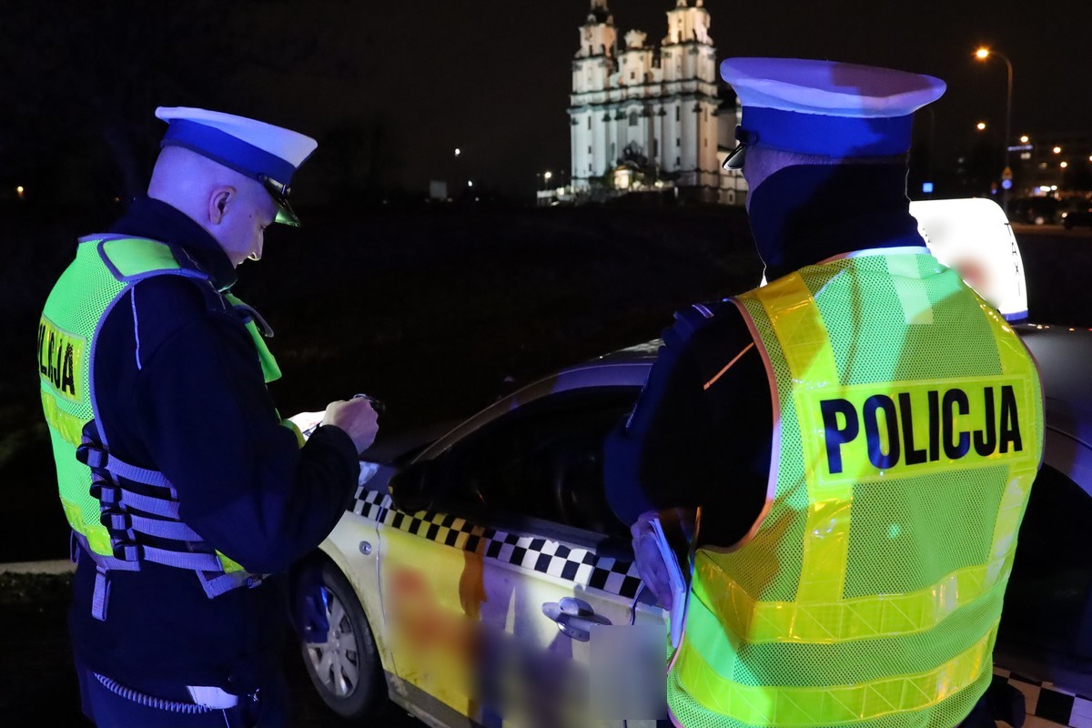 Dwóch policjantów stoi obok taksówki
