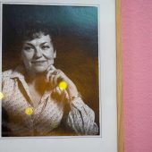 Czarno-biała fotografia kobiety w średnim wieku na różowej ścianie.