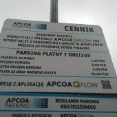 Tablica z cennikiem obok parkometru