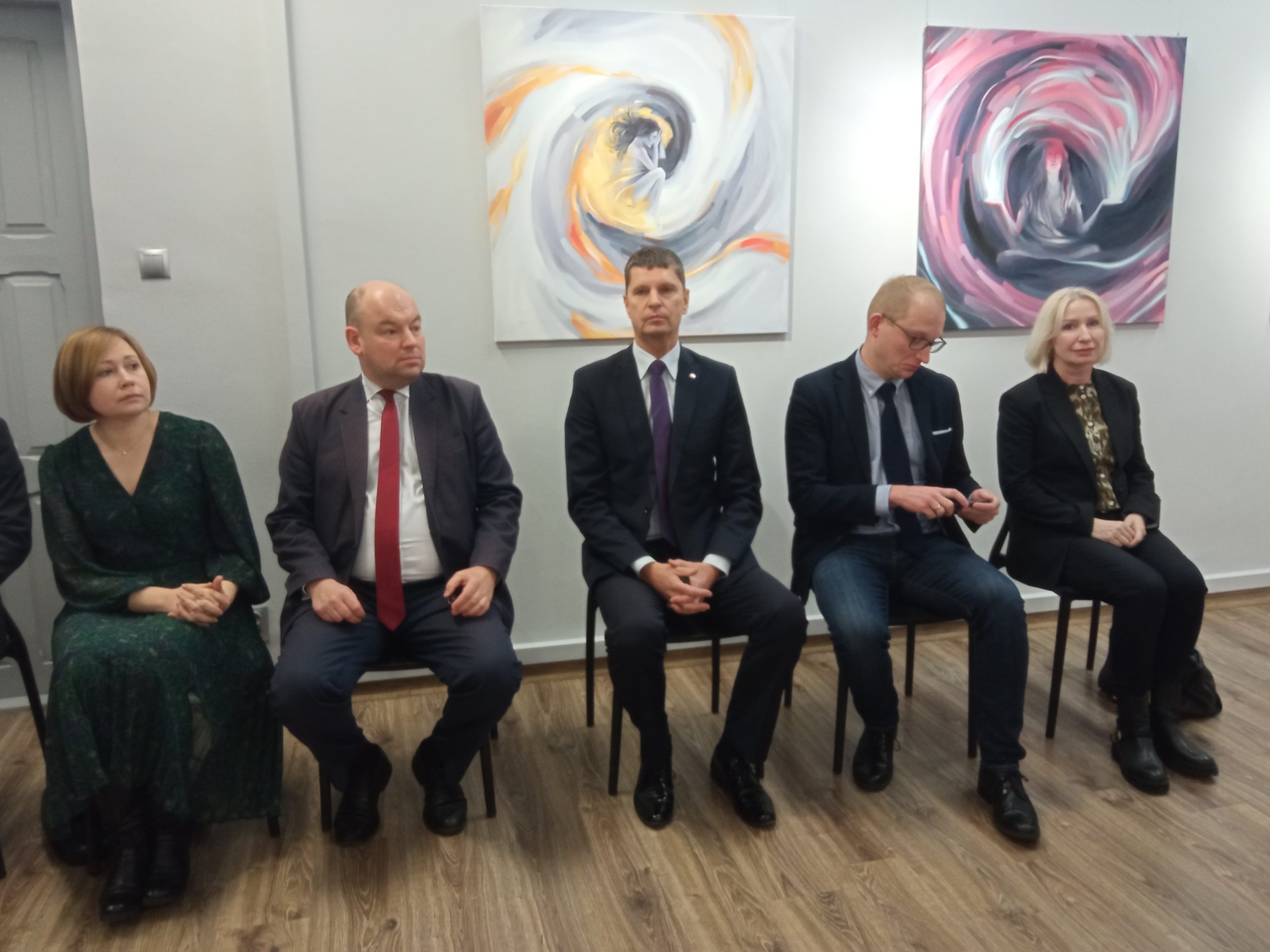 Dwie kobiety i trzech mężczyzn siedzi obok siebie na krzesłach