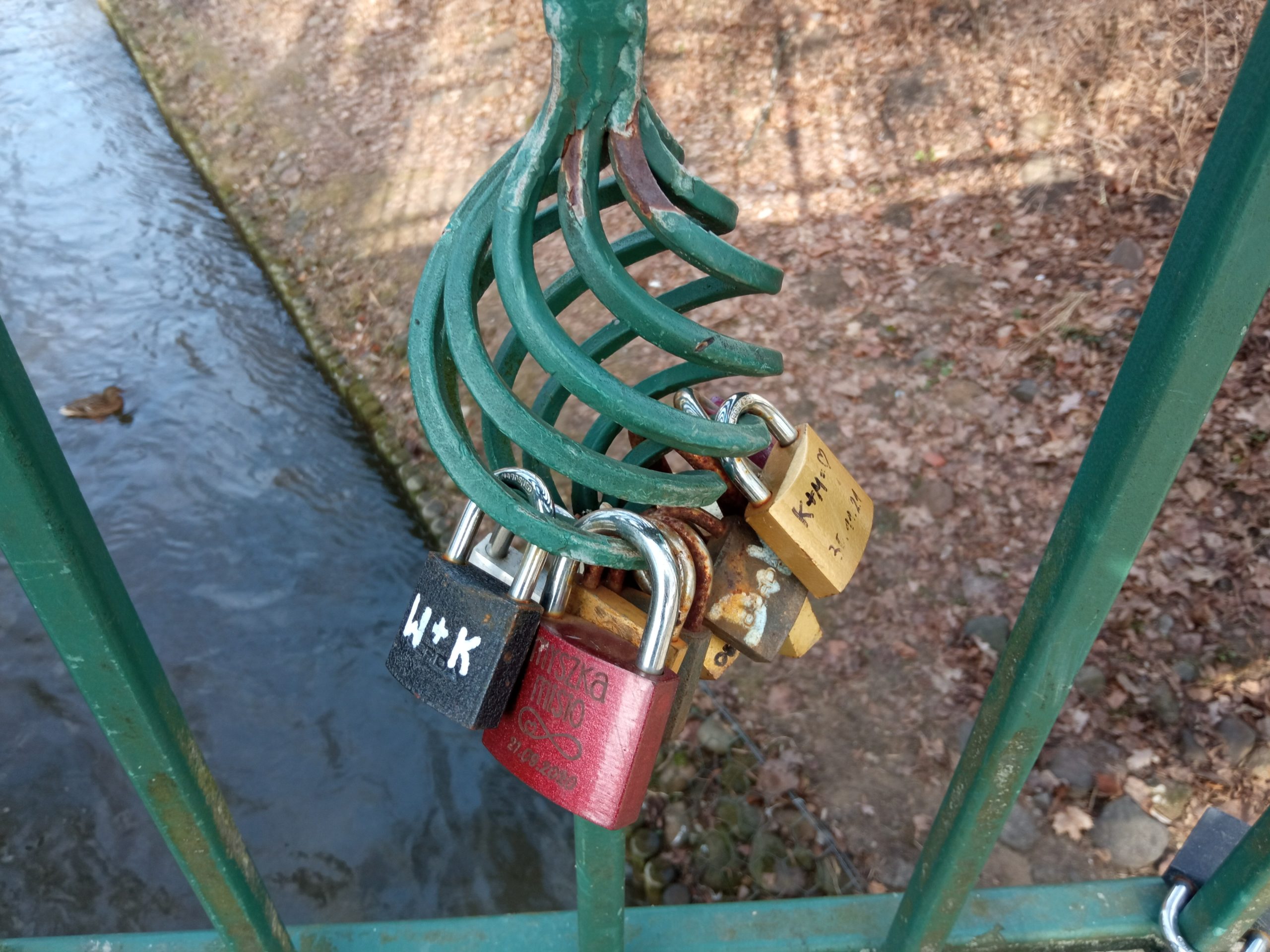 Kolorowe kłódki wisza na balustradzie mostka