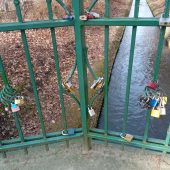Kolorowe kłódki wisza na balustradzie mostka