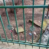 Kolorowe kłódki wiszą na balustradzie mostka; poniżej płynie rzeka