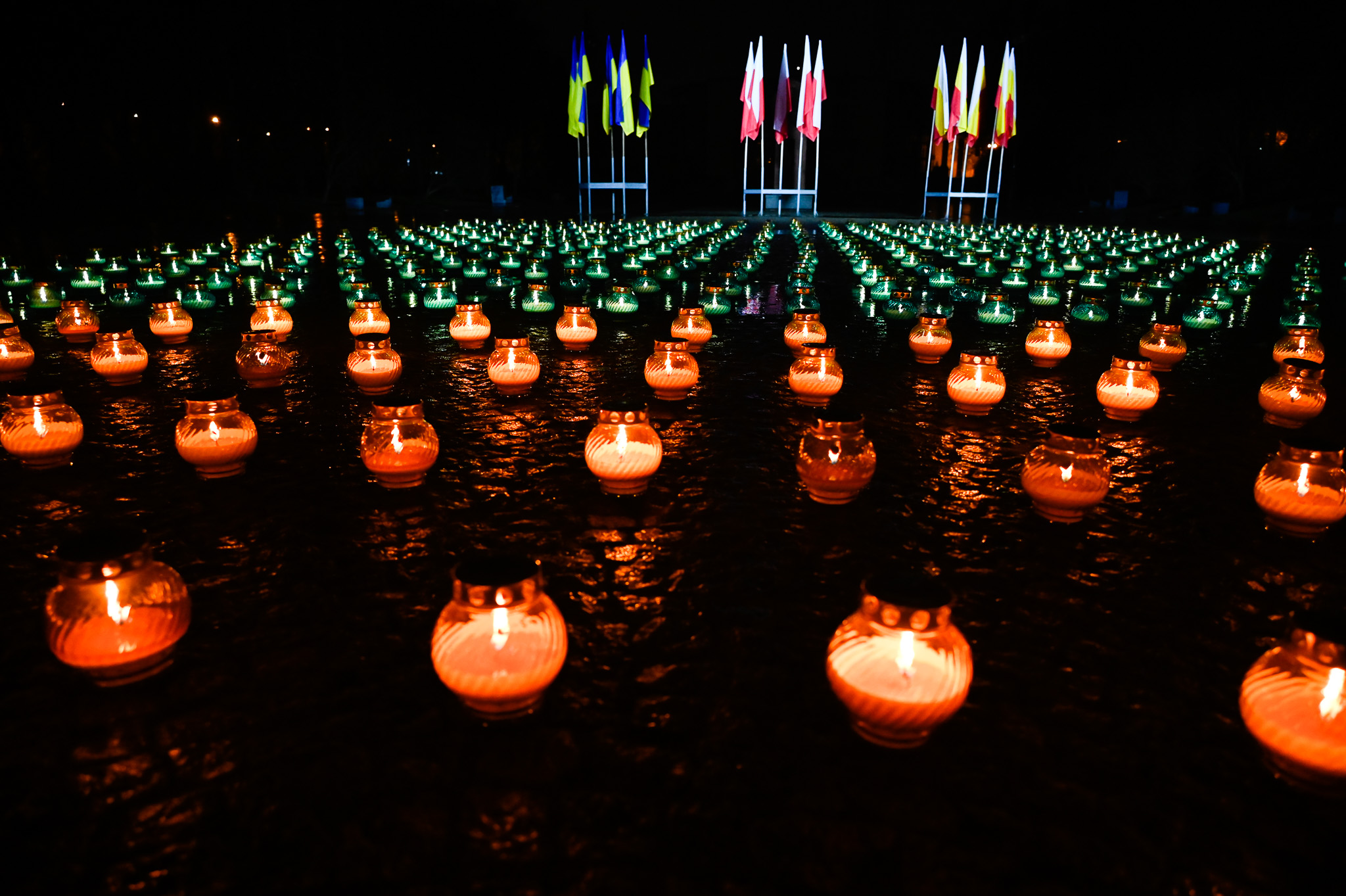 Nocą znicze palą się przed flagami