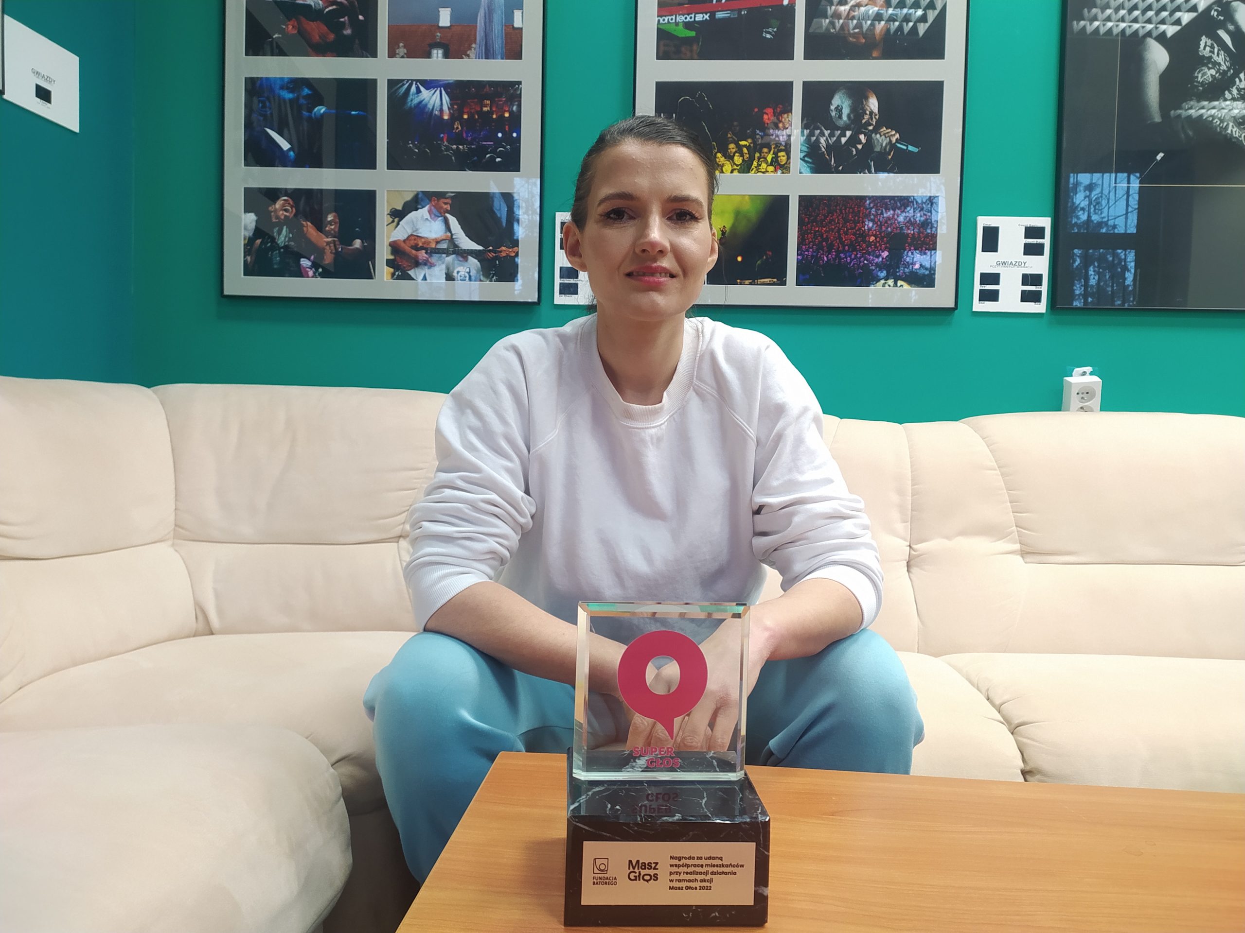 Kobieta siedzi na sofie przed niskim stolikiem, na którym stoi statuetka.