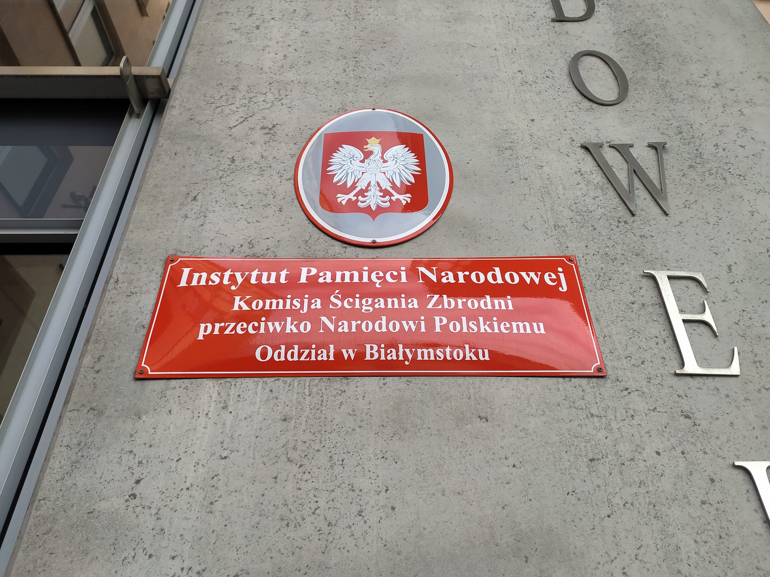 Czerwona tabliczka i godło Polski wiszą na ścianie budynku