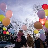 Ludzie wypuszczają z rąk kolorowe balony
