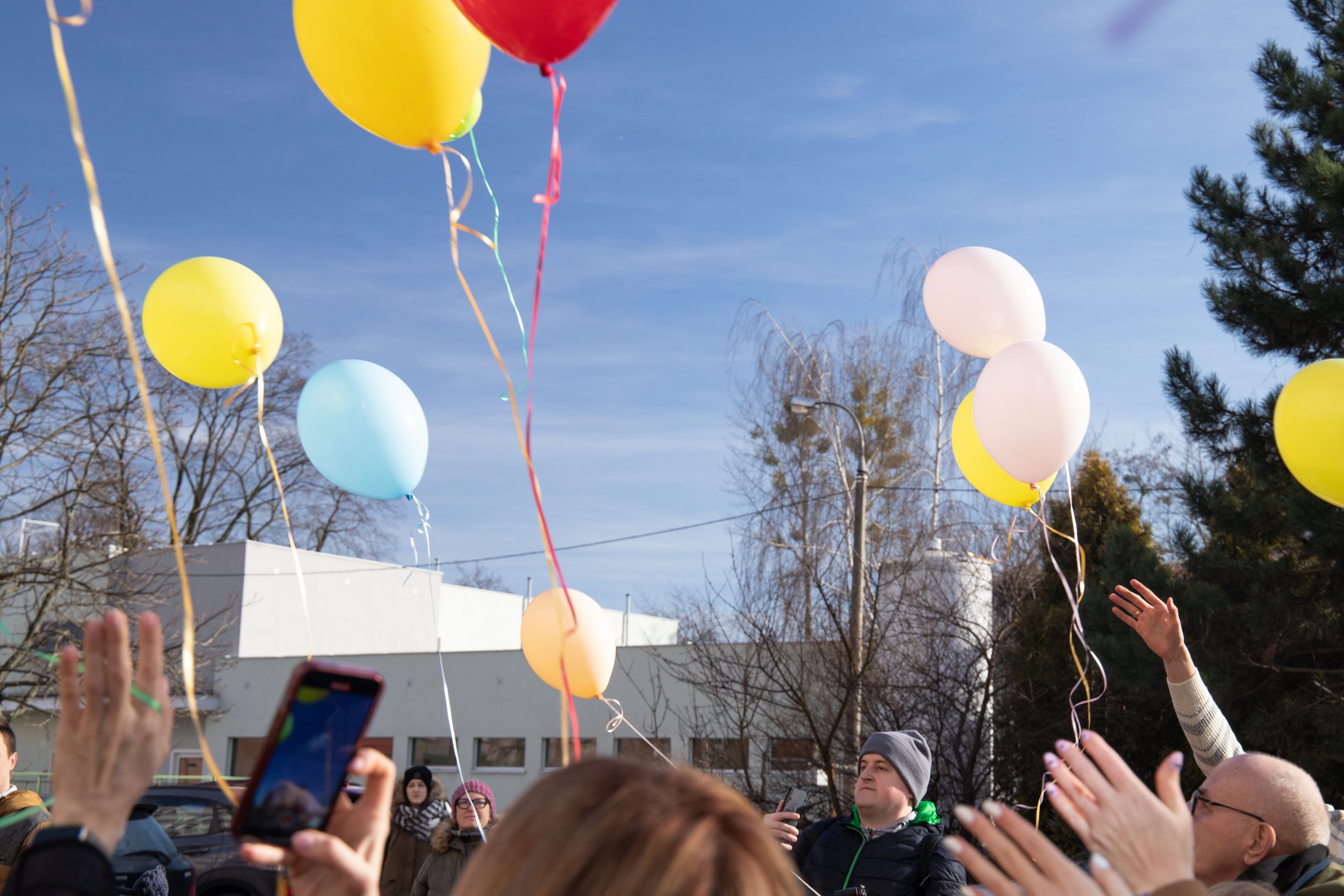 Ludzie wypuszczają z rąk kolorowe balony