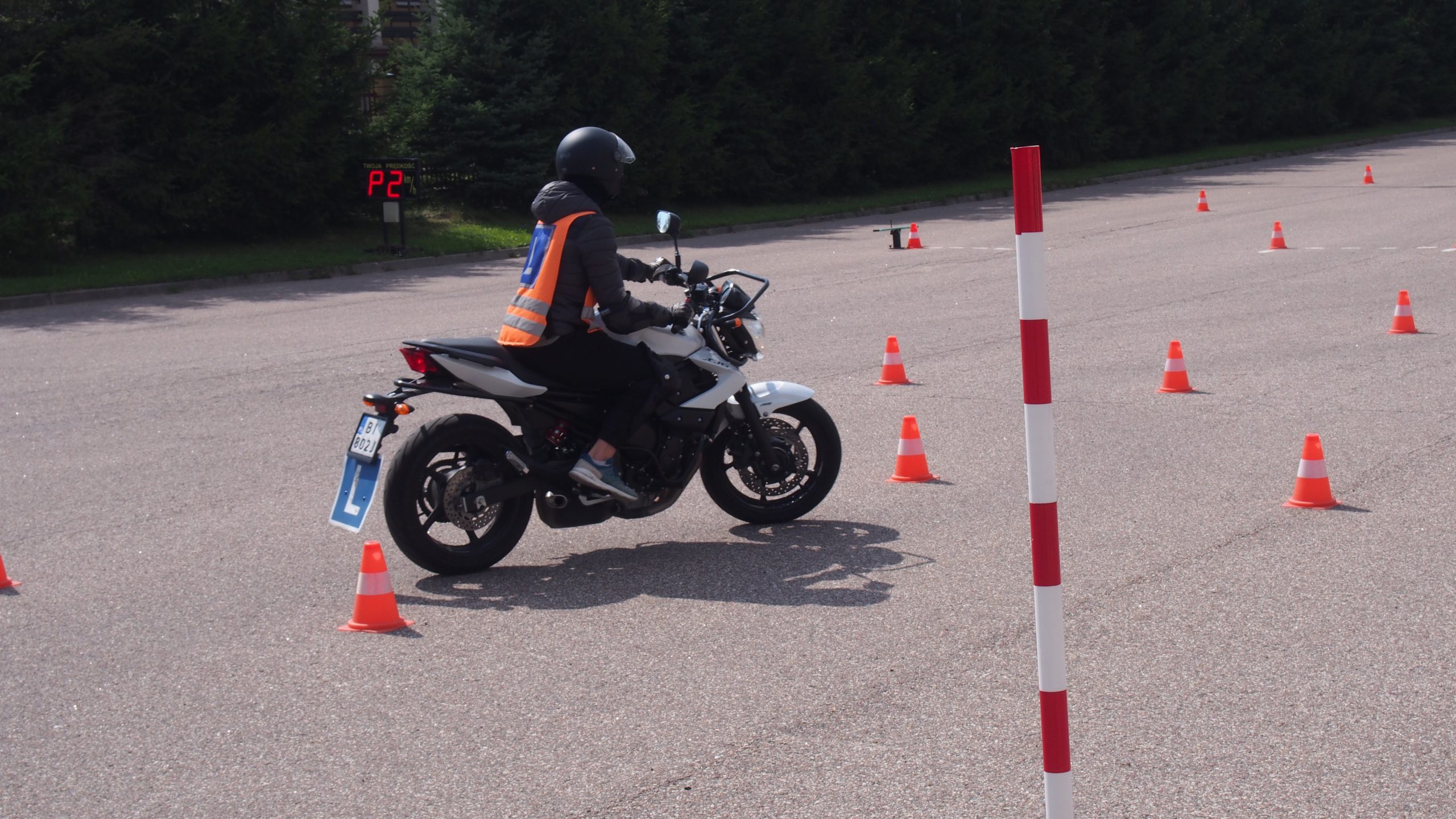 Motocyklista jedzie motorem po placu egzaminacyjnym.