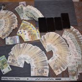 Na stole leżą zabezpieczoen banknoty i telefony komórkowe