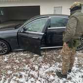 Funkcjonariusz stoi obok czarnego samochodu