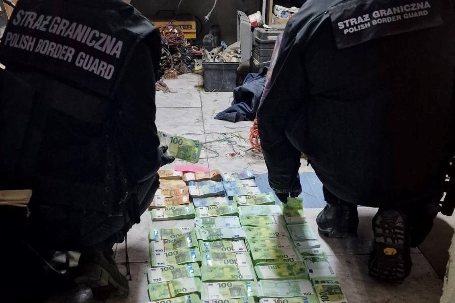 Dwie osoby przeliczają leżace na posadzce zabezpieczone pieniądze