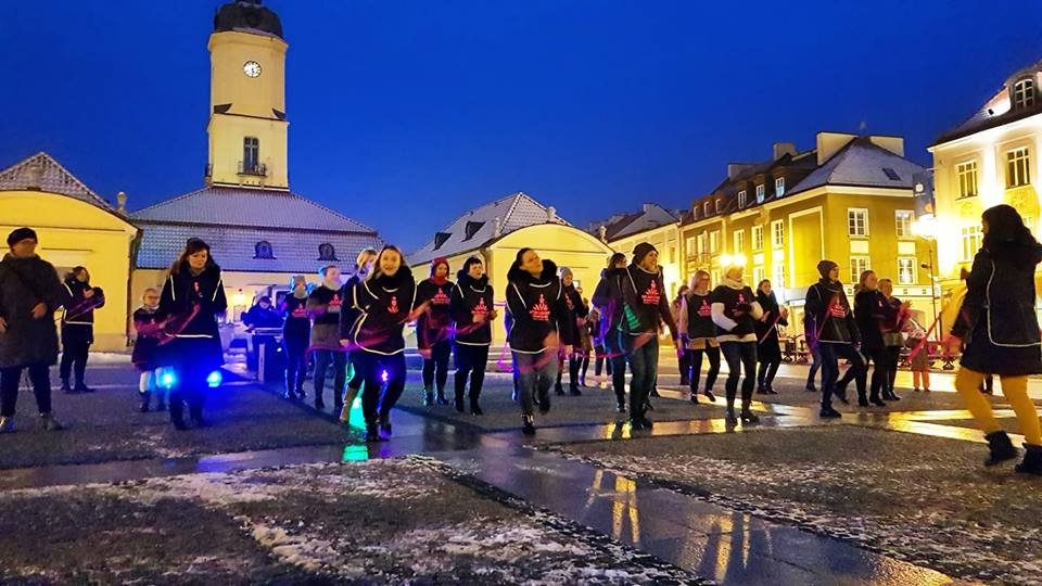 Grupa kilkudziesięciu kobiet tańczy na placu przed ratuszem.