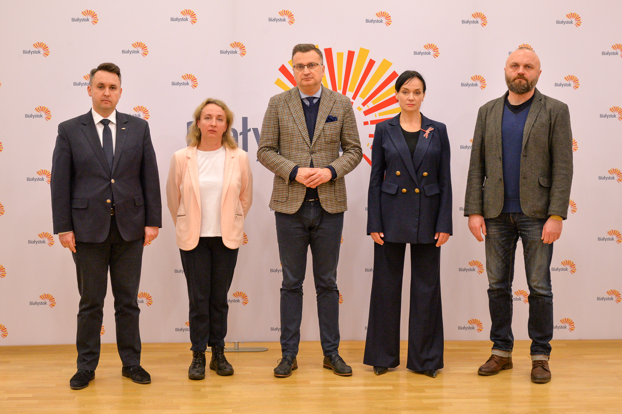Pięć osób stoi na tle baneru promującego Miasto Białystok.