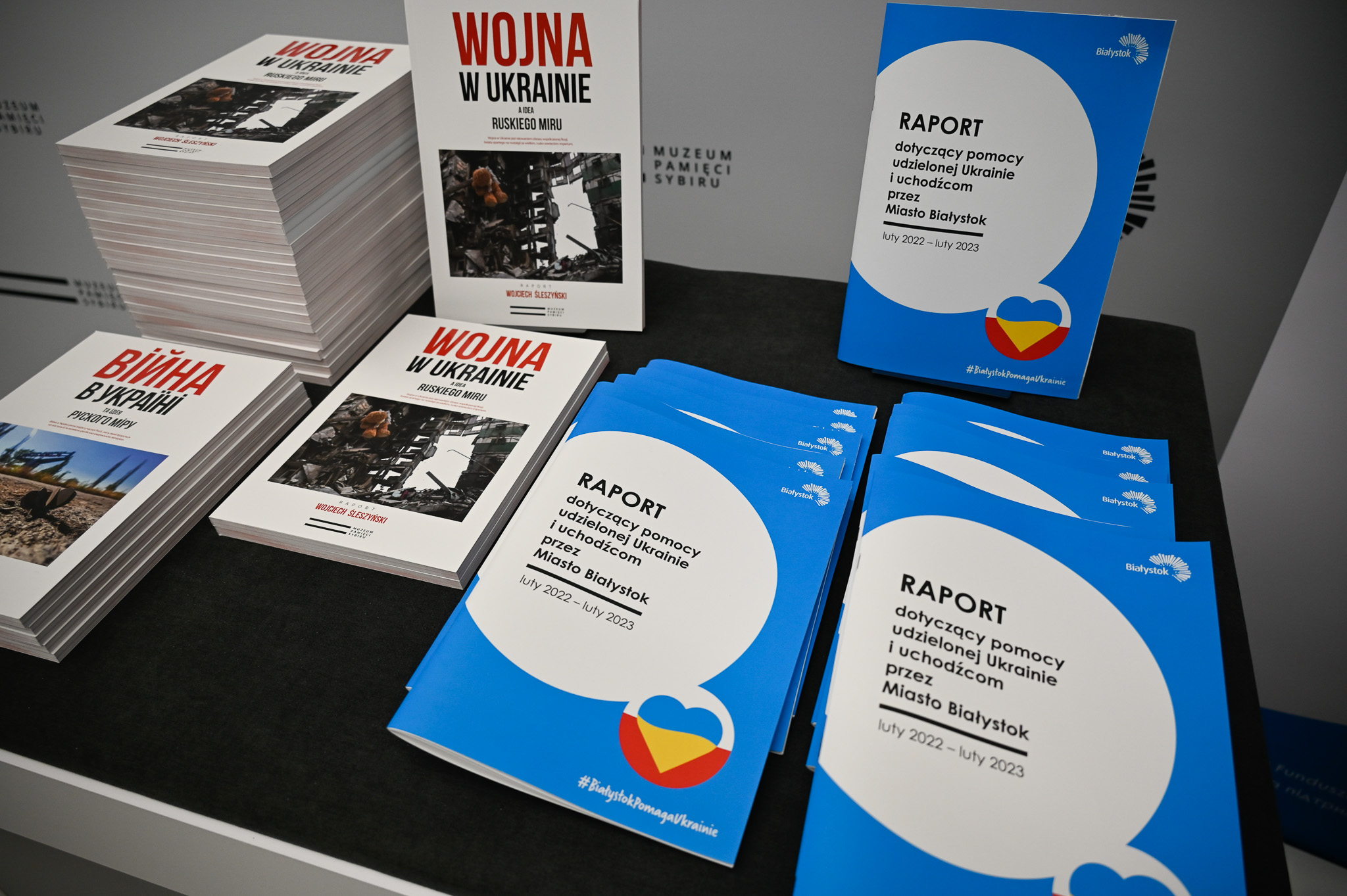 Wydrukowany w formie biuletynu raport oraz książka leżą na stoliku