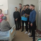 Panowei wręczają kwiaty i składają życzenia pacjentce szpitala