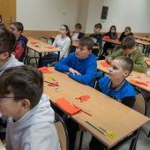 Uczniowie siedzą przy stołach słuchają wykładu