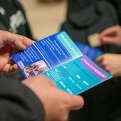 Na zdjęciu widać dłonie trzymające ulotkę.