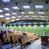 Aula, w której siedzą studenci, a na katedrze ktoś przemawia.