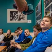Grupa uczniów w studiu radia, jeden z nich mówi do mikrofonu