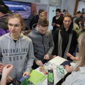 Młodzi ludzie stoją przy stoisku firmowym.