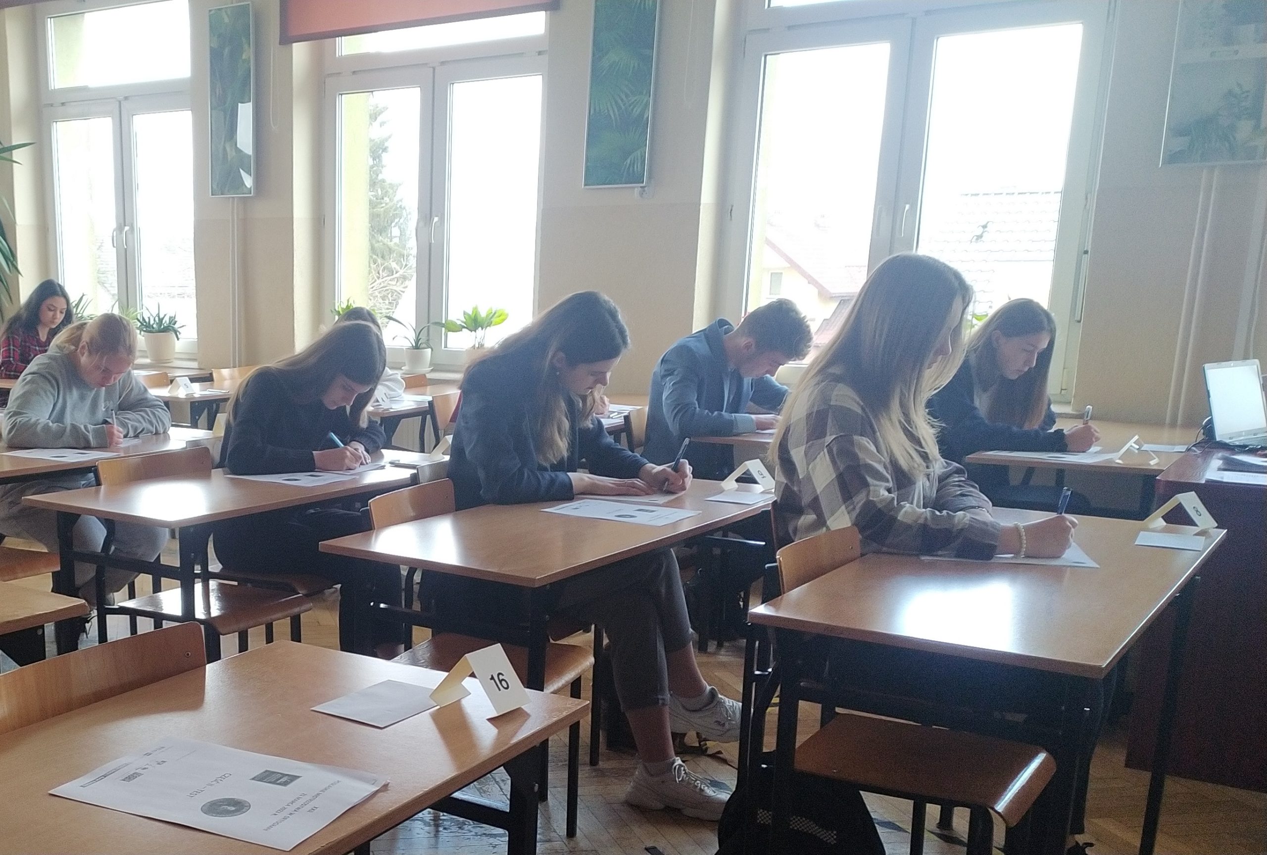 Uczniowie siedzą w ławkach w klasie