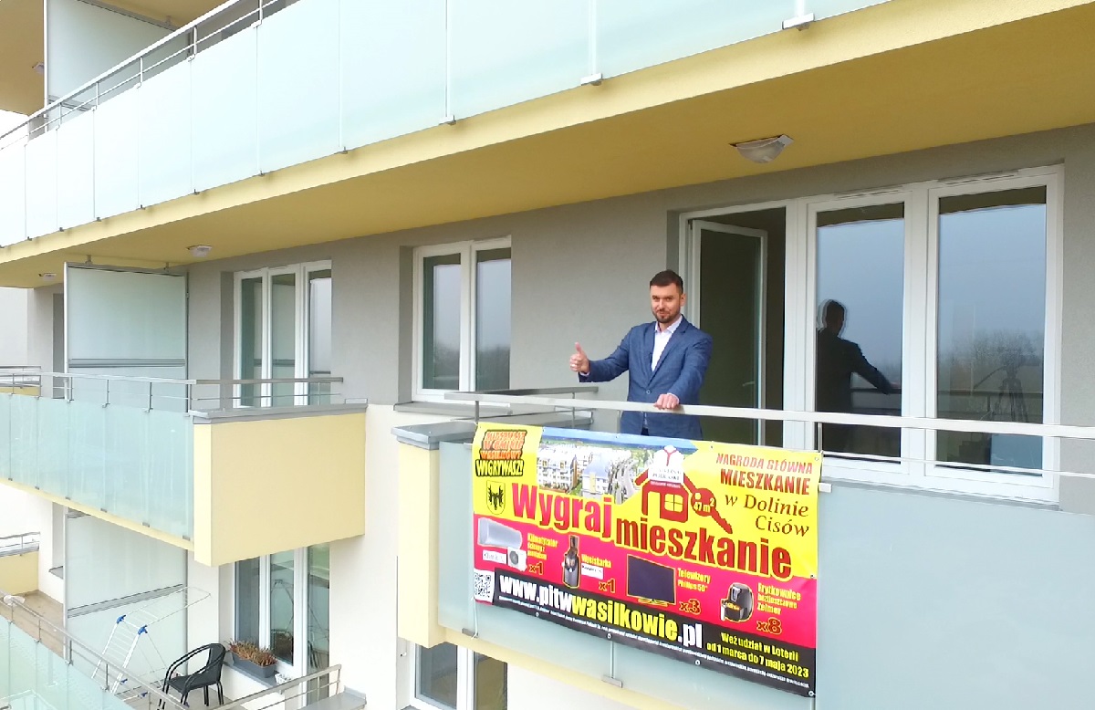 Mężczyzna stoi na balkonie w bloku wielorodzinnym.