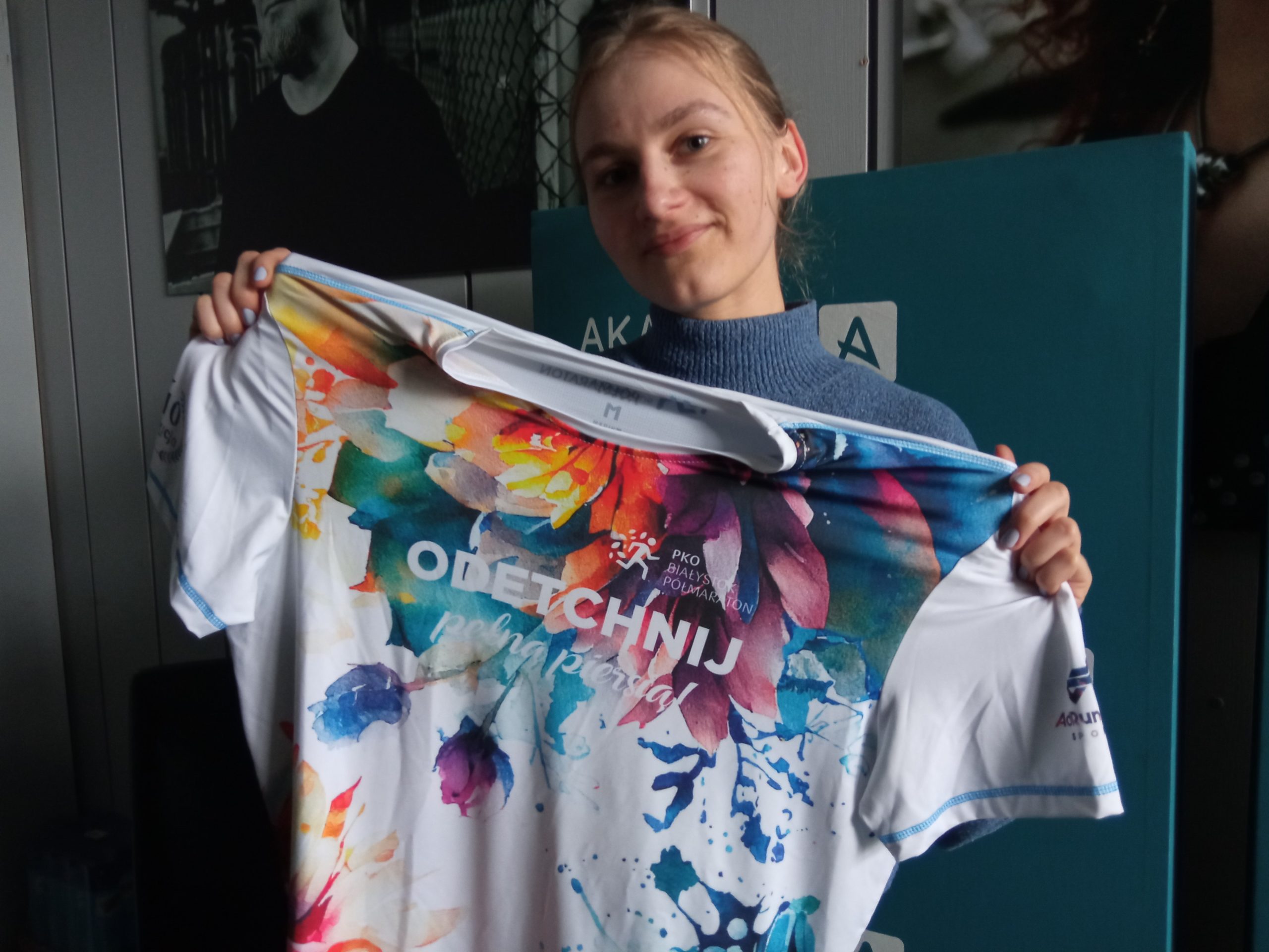 Młoda kobieta prezentuje kolorową koszulkę biegową