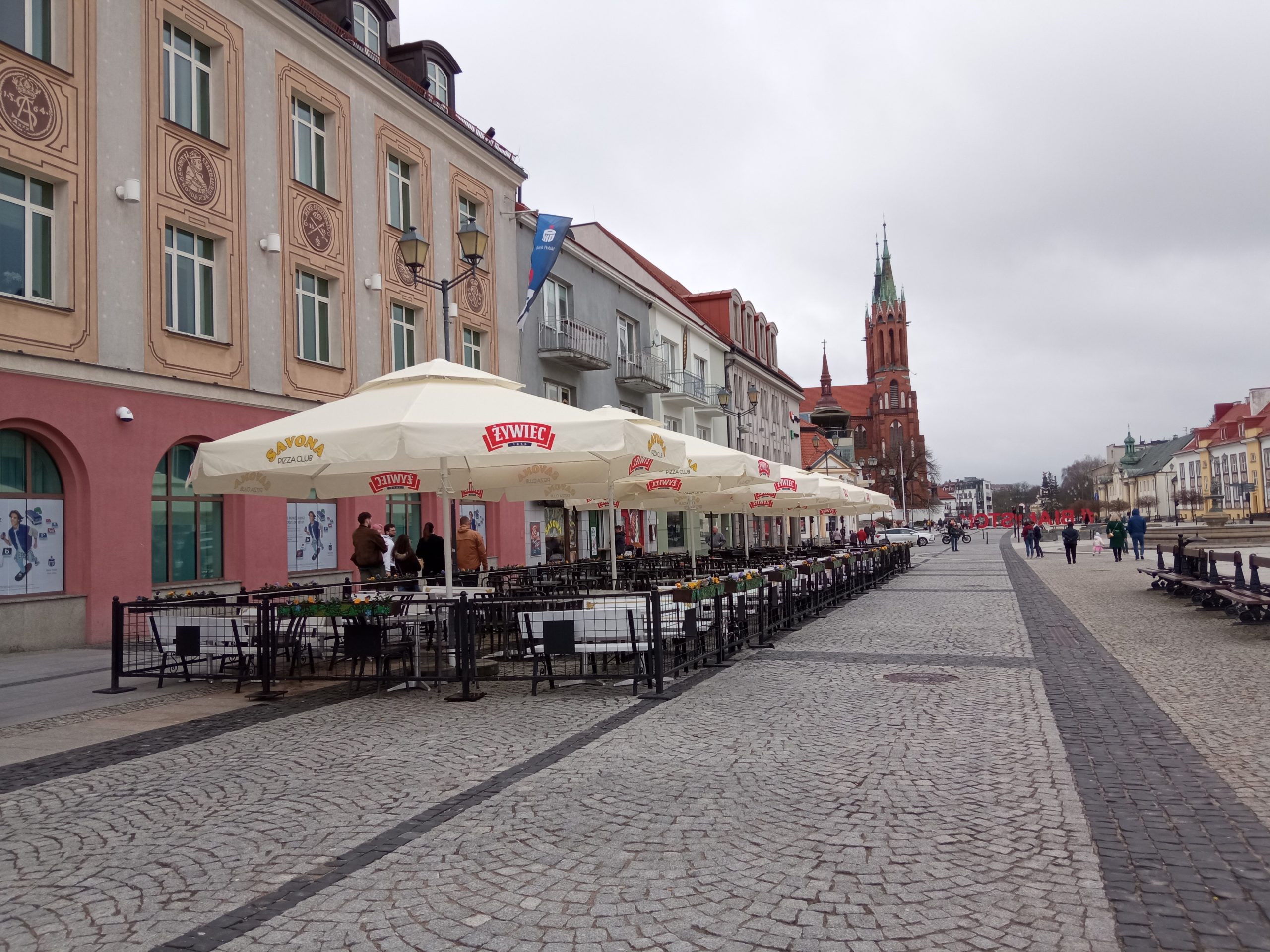 Rozstawione stoliki z parasolami i krzesełkami na rynku, wzdłuż chodnika